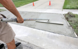 This image shows a man leveling a cement in the driveway.